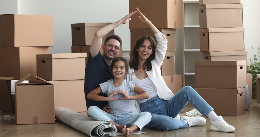 Happy family with little daughter enjoy move-in day to new, own, rented house, young parents showing with joined hands roof over their heads, cute girl make heart symbol with arms. Relocate, bank loan Royalty-Free Stock Footage #1102066321