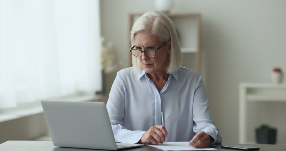 Concerned mature businesswoman sit at desk, work use laptop, doing paperwork, annoyed about problem, experiences negative emotions, going through crisis, bankruptcy, late payment, leaves the workplace Royalty-Free Stock Footage #1102066403