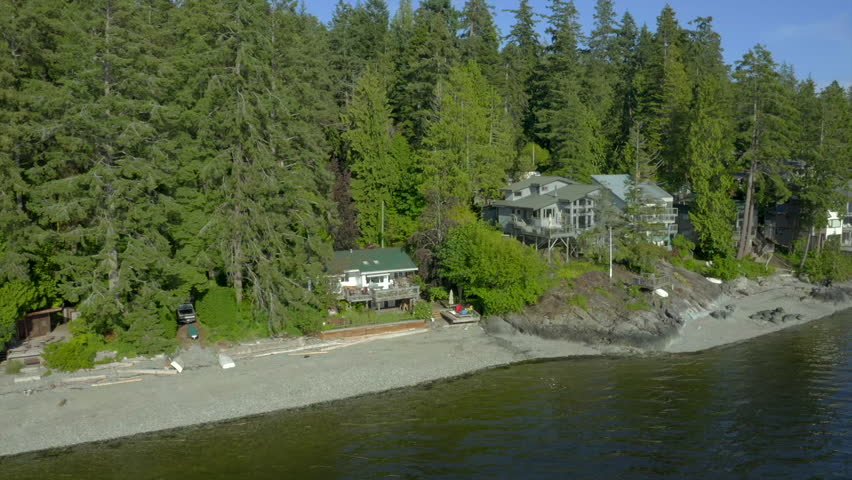 Establishing aerial shot of ocean beach with rocks and pebbles in slow motion at summer day in Vancouver, Canada, North America. Day time on September 2022. Drone forward. ProRes 422 HQ.