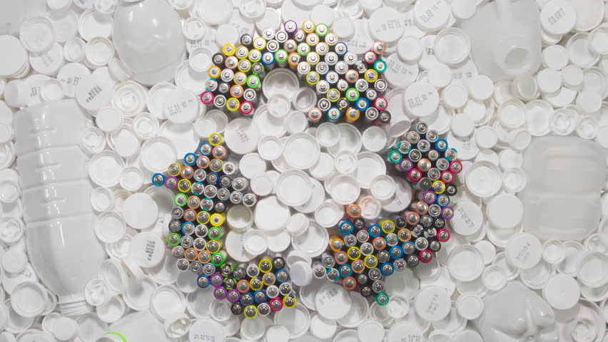 Collecting Plastic Lids for Recycling. HD Loop. The recycling symbol is made up of old AA batteries. It rotates slowly among white plastic milk and yoghurt bottles and lids