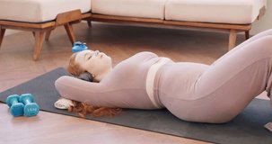 young calm relaxed woman lying on a sports mat at home and listening to music on headphones. red head girl having rest after workout relaxation hobby interets lifestyle