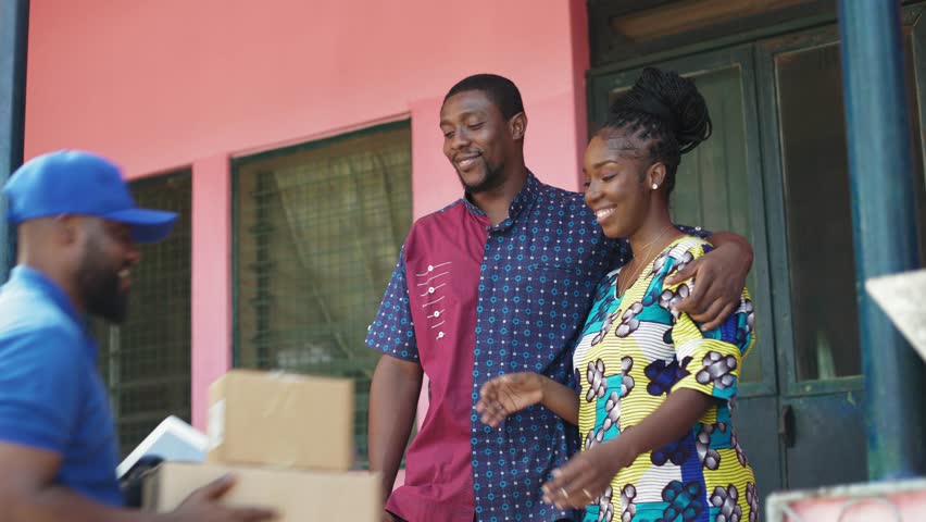 Excited Young Black African Couple receive cardboard boxes with products purchased online from delivery man, through local postal shipping and delivery parcel service. Royalty-Free Stock Footage #1102067253