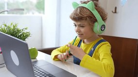 Cute smart caucasian using laptop. Online tutor teaching digital class, web lesson on computer at home. Virtual education. Schoolboy girl studying write exercise doing homework.