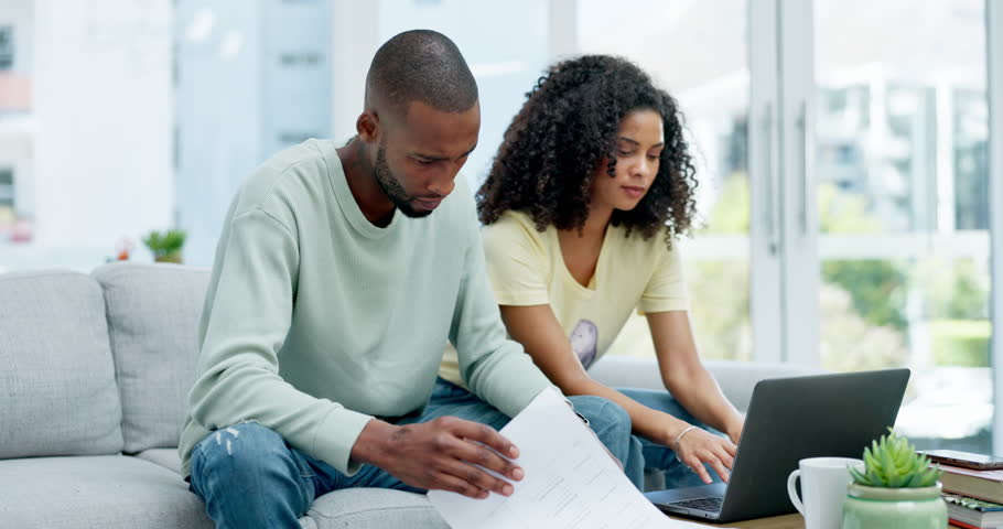 Sad, laptop and couple with paperwork for finance debt, taxes or expenses on sofa in home. Interracial, documents and woman comfort and hug depressed black man for problem, bills or financial crisis. | Shutterstock HD Video #1102068881