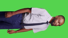 Vertical video: Side view of african american man standing over greenscreen backdrop, wearing formal suit for corporate office job. Male employee businessman feeling stylish and positive, green screen