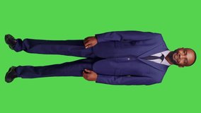 Vertical video: Front view of smiling startup worker showing thumbs up sign and expressing approval in studio, full body greenscreen. Corproate manager feeling confident and positive, doing like and