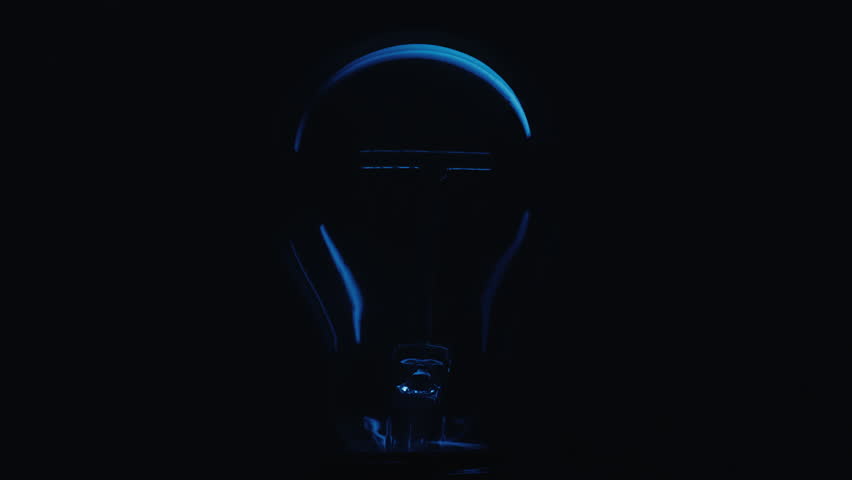 Close up shot of the filament inside a decorative incandescent bulb turning on, glowing dimly and turning off