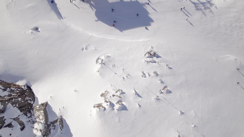 Top down of chairlift, aerial drone footage ski hill on a sunny day, Whistler BC, ski run, skier, winter sport. 4K 24FPS.