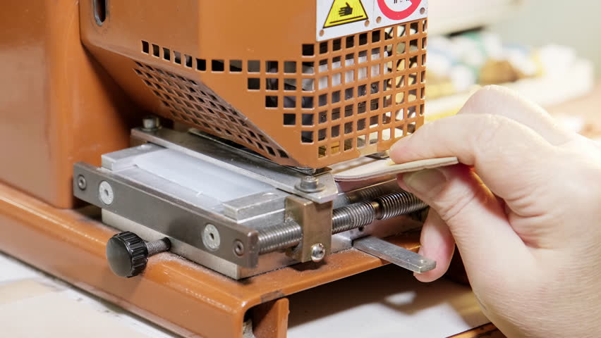 Machine stamping watchband. Industry concept. Working stamp machine. Employee works at factory. Leather strap. Close-up in 4K, UHD
