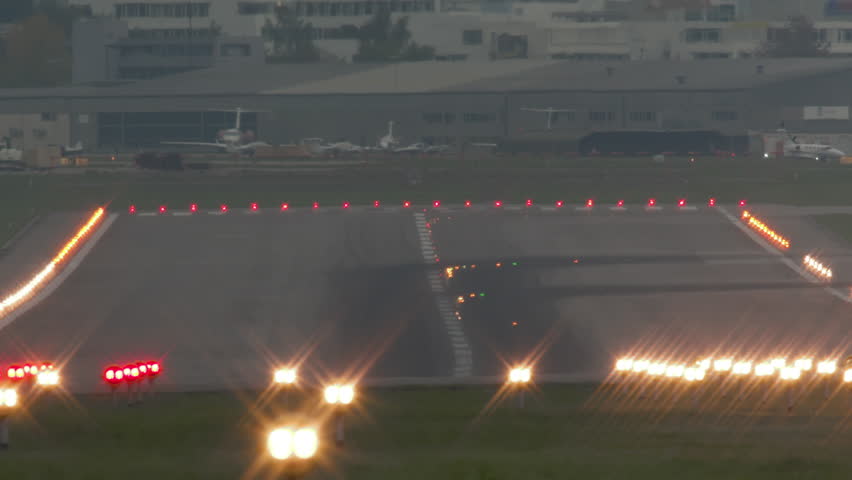 A commercial airplane is captured in slow motion as it lands on the runway at Zurich Airport, on a grey and misty day