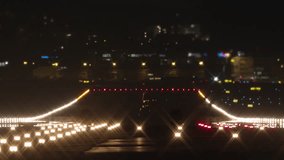 A slow-motion video featuring a dark silhouette of an airplane landing from behind, illuminated by the bright lights of the runway