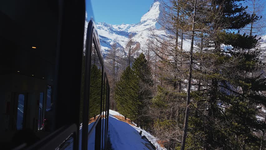Riding the iconic cogwheel Gornergrat railway in Zermatt ski resort in the Swiss Alps in Valais, Riding a train in Switzerland on a sunny winter day