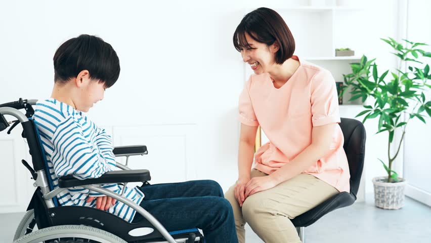 A medical worker examining a boy in a wheelchair. | Shutterstock HD Video #1102076951