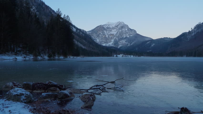 Langbathseen, Ebensee, Austria. Beautiful, cold morning in the austrian alps. Clear sky, golden sunlight hitting the mountain in the background. Clear water reflecting the alps. Snowy winter forrest,