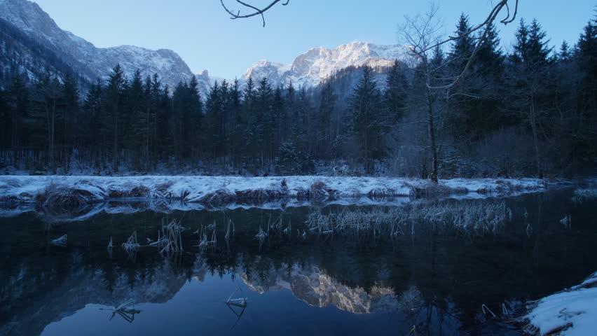 Langbathseen, Ebensee, Austria. Beautiful, cold morning in the austrian alps. Clear sky, golden sunlight hitting the mountain in the background. Clear water reflecting the alps. Snowy winter forrest,