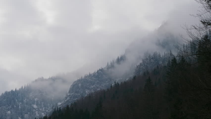 Ebensee, Austria. Mountaintop the austrian alps on a moody, cloudy day. Clouds covering the snowy, frozen forrests. 