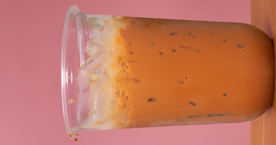 4K footage vertical video Front view SLO MO CU, iced tea in a clear glass filled with ice and milk to finish off. Royalty-Free Stock Footage #1102084129