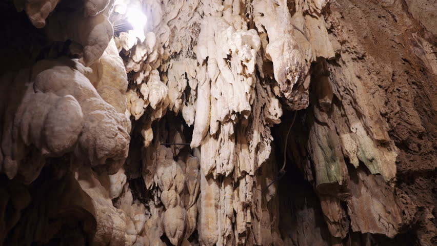 Rocky terrain inside a naturally formed cave with stalactites hanging from the ceiling and stalagmites rising from the floor behind the waterfall in Edessa Northern Greece.