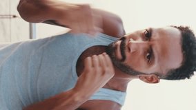 VERTICAL VIDEO: Close up, young bearded male fit athlete boxer practicing punching technique while standing on the embankment