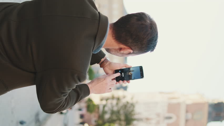 VERTICAL VIDEO: Man takes photo standing on the square of the old city. Back view