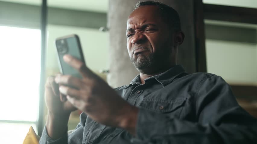 Portrait of handsome mature african american man browse products in internet online shopping store planning trip travel or swiping through profiles on dating app on smartphone at home Choice concept