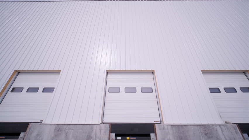 Construction process of a big, modern warehouse with multiple garage gates for easy access and transportation of goods. Royalty-Free Stock Footage #1102090833