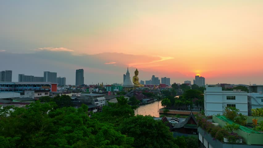 
aerial view golden big Buddha Wat Paknam Phasi Charoen in sunset. 
beautiful sunset reflection on a canal in front big buddha. 
scenery sky in twilight background.the one famous landmarks in Thailand