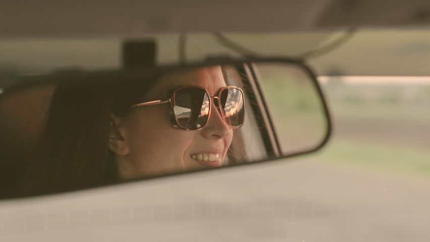 Girl driver driving her car. Free young woman traveling by car. Young female driver in sunglasses in the reflection of the rearview mirror. Weekends, car, adventure, road and sports. Taxi Royalty-Free Stock Footage #1102096349
