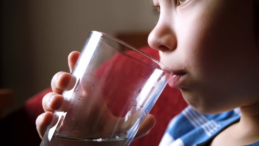 The child is drinking water from glass beaker. Closeup side view. Healthy habit. Water balance. Health care. Energy drink. Useful liquid. Tasty. Quench thirst. Swallows clean and fresh spring water. Royalty-Free Stock Footage #1102097439