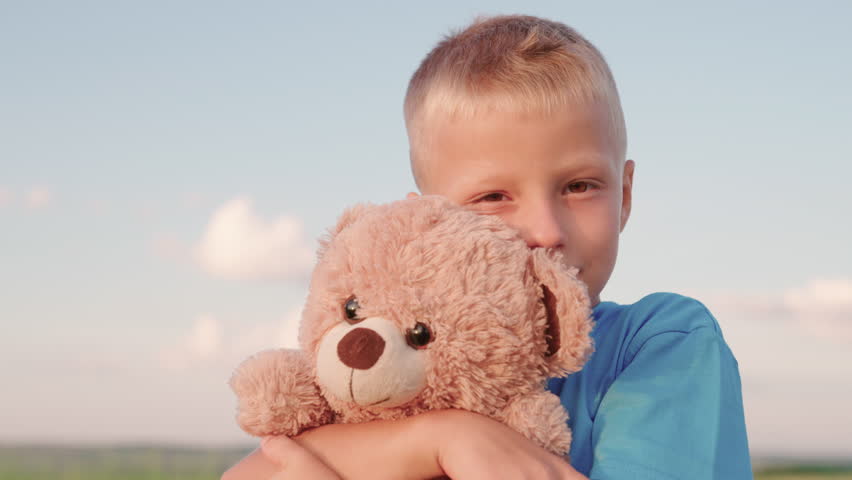 Cute chilld baby boy hugs his favorite soft teddy bear on playground. Child plays with Teddy bear. Plush toy in hands of boy, child in summer park. Kid plays with toy. Portrait of child with bear toy Royalty-Free Stock Footage #1102098475
