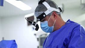 Male surgeon in headlight, mask and cap working in surgery room. Doctor uses tool device and looks at screen. - Powered by Shutterstock - Get 15% off with code: PIKWIZARD15