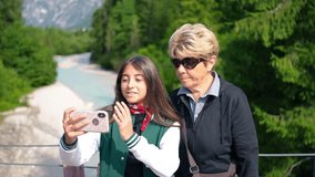 A young girl taking a selfie with her grandmother along a mountain river - Powered by Shutterstock - Get 15% off with code: PIKWIZARD15