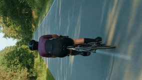Fitness woman riding bicycle. Woman cycling on road bike on empty asphalt road. Vertical video. Sport concept. Woman on bicycle. Female cycling training. Fitness cardio exercises. Active workout