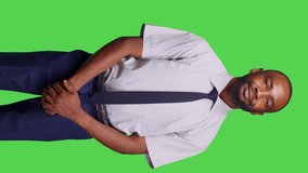 Vertical video: Front view of young businessman posing on greenscreen background, wearing office suit for startup company job. Male corporate worker feeling stylish and confident, green screen mockup