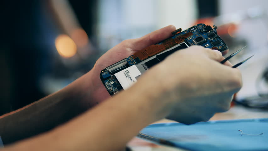 Elements of a dismantled gadget in the hands of a repairman