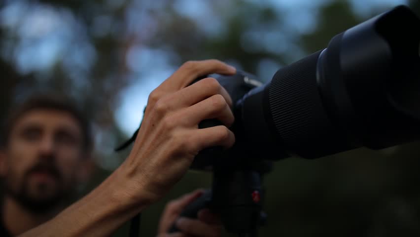 a man takes pictures with a camera in the forest. photographer taking pictures of nature, camera with large lens close-up