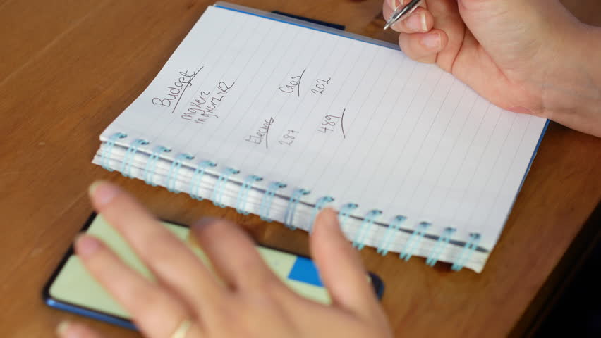 Woman calculating family finances budget on calculator and writing in notebook. | Shutterstock HD Video #1102104651