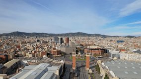 Panoramic aerial drone view of city traffic Plaza de Espana of Squares in Barcelona with Venetian Towers and Arenas de Barcelona. Cars driving around monumental fountain of Placa de Espanya. 4K video