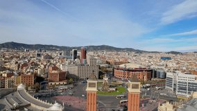 Panoramic aerial drone view of city traffic Plaza de Espana of Squares in Barcelona with Venetian Towers and Arenas de Barcelona. Cars driving around monumental fountain of Placa de Espanya. 4K video