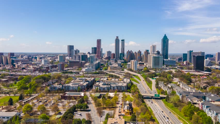 hyper lapse aerial drone footage of Atlanta Georgia downtown area near the express way. the skyline is vibrant blue show casing the beautiful metropolises. related to urban travel, and architecture 