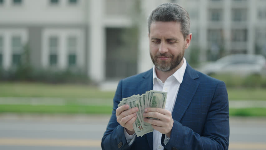 Slow motion of man counting money outdoor. Portrait business man holding cash dollar bills outdoor. Big luck, banner. Dollar cash money concept. Rejoices to win cash. Financial luck and success.