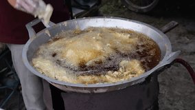 Close-up video of an Indonesian street food seller frying tofu dough in a pan with hot oil