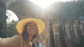 Young woman taking cool selfie video traveling in Sri Lanka in famous social media destinations. Girl video chatting online using phone sharing with friends adventures in Asia 
