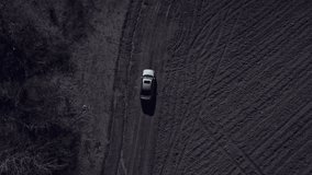 Aerial top view of grey car drives alone off-road on dirty rural roads filming by drone.