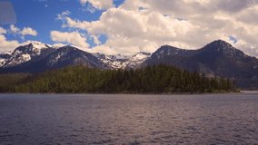 Summer boat ride on Lake Tahoe with forests and snowy Sierra Nevada Mountains in the background. 4K UHD video.