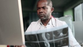 Confident busy mature african american doctor therapist looking at computer screen typing browsing working online distance remote and make notes in patient's medical card at modern hospital indoors - Powered by Shutterstock - Get 15% off with code: PIKWIZARD15