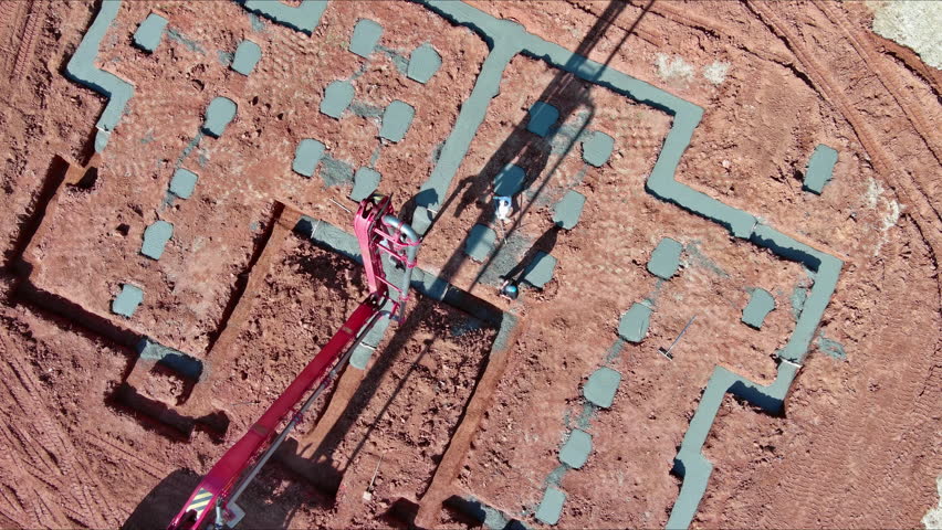 Construction worker is pouring cement concrete by using an automatic pump to lay foundation for building