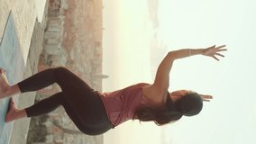 VERTICAL VIDEO: Girl practices handstand yoga asana at lookout point at dawn