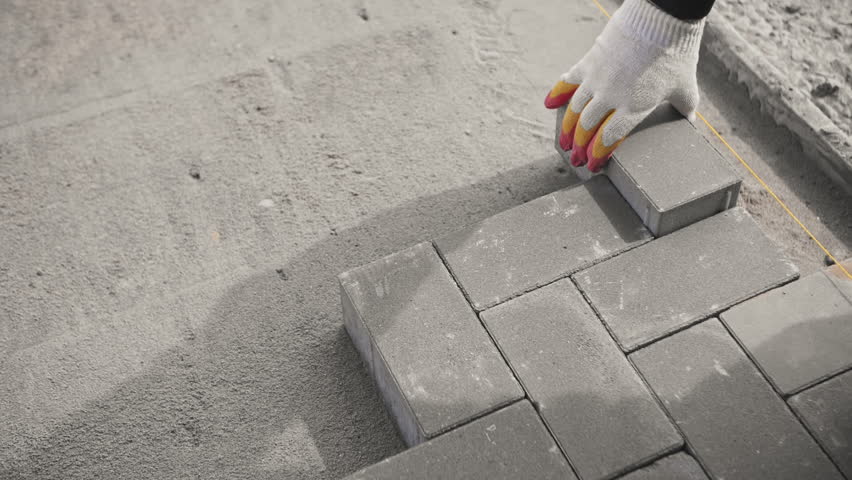 worker lays pavement tiles on the site of a residential building Royalty-Free Stock Footage #1102131153