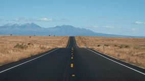Driving vehicle on highway of black and yellow road markings at sunny day, road going into distance through desert prairie to high mountains on horizon, in Western Usa. Pov from riding car - Powered by Shutterstock - Get 15% off with code: PIKWIZARD15